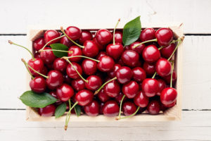 Cherries in a wooden crate on a white background.